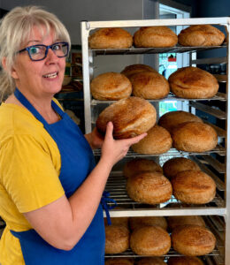 Autumn Sissons holding fresh-baked bread at Table Ready Meal Prep in Tulsa