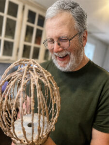 Scott, co-founder of Table Ready Tulsa, laughing in the kitchen while holding a batter-covered mixer whisk.
