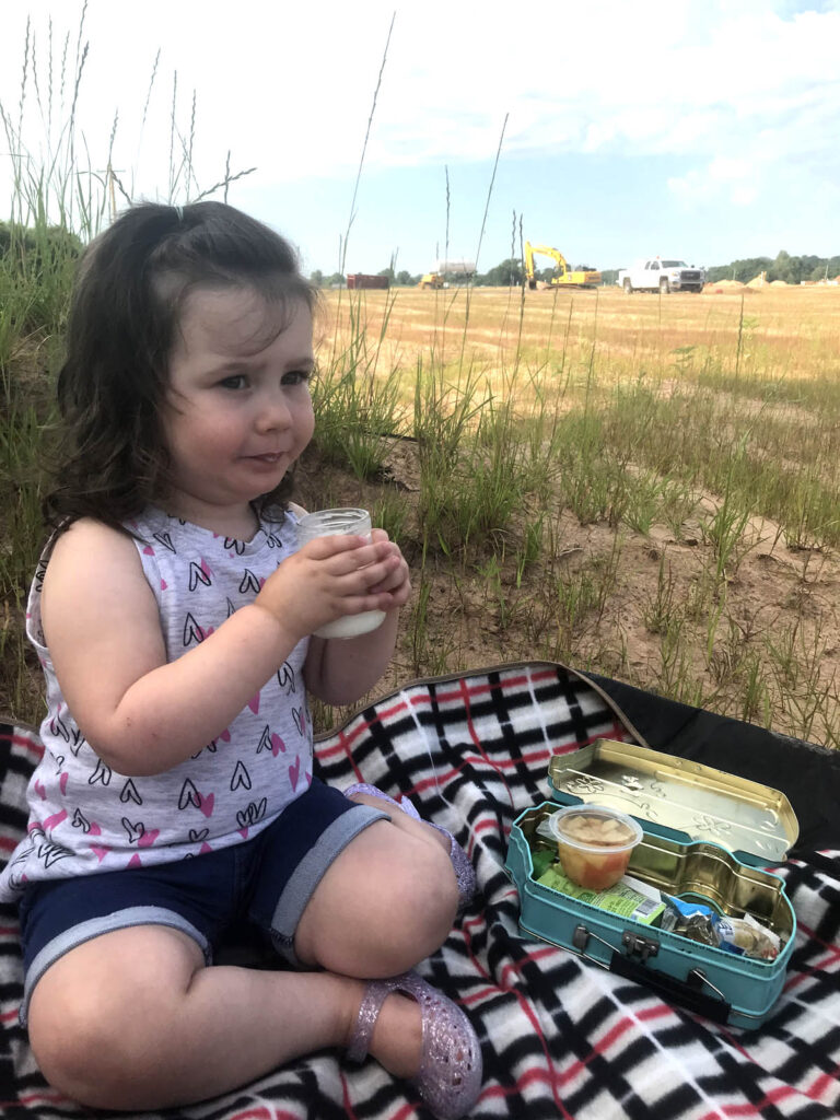 Little girl watching heavy equipment at a picnic outdoors